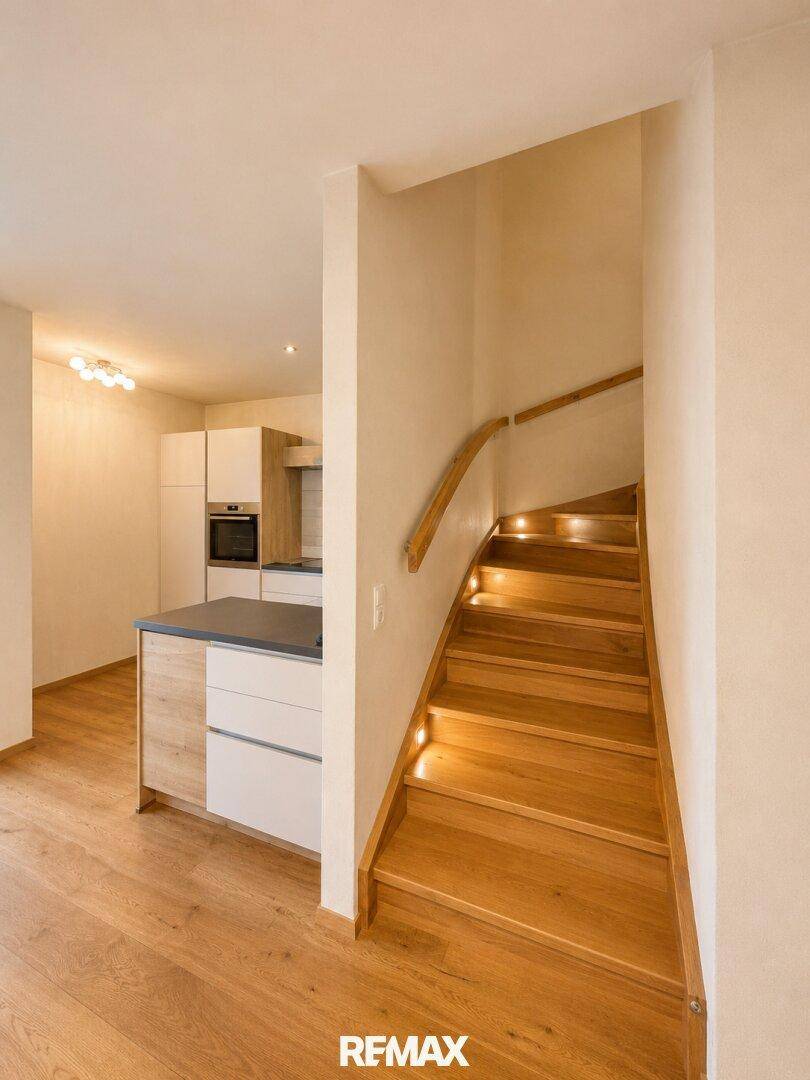 Elegante Holztreppe mit integrierter Beleuchtung, die in die oberen Stockwerke führt.