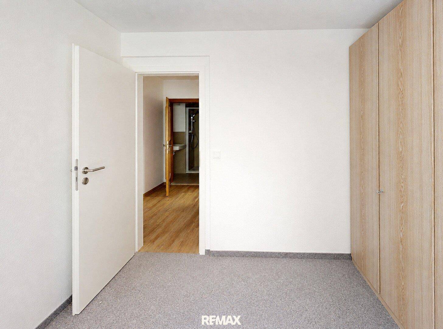 Leeres Schlafzimmer mit Teppichboden und eingebauten Holzschränken, bietet viel Stauraum.