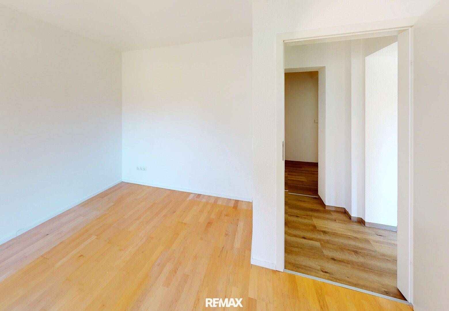 Leeres Schlafzimmer mit hellem Holzfußboden und weiß gestrichenen Wänden, bereit zur Einrichtung.