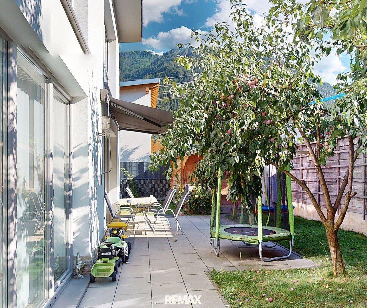 Gartenbereich mit Terrasse, Trampolin und Obstbaum, ideal für Familienaktivitäten.