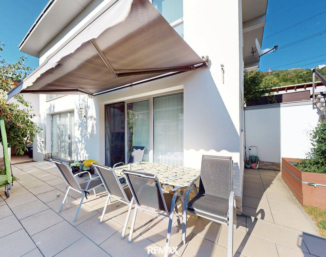 Gemütliche Terrasse mit Markise und Gartenmöbeln, ideal für entspannte Stunden im Freien.