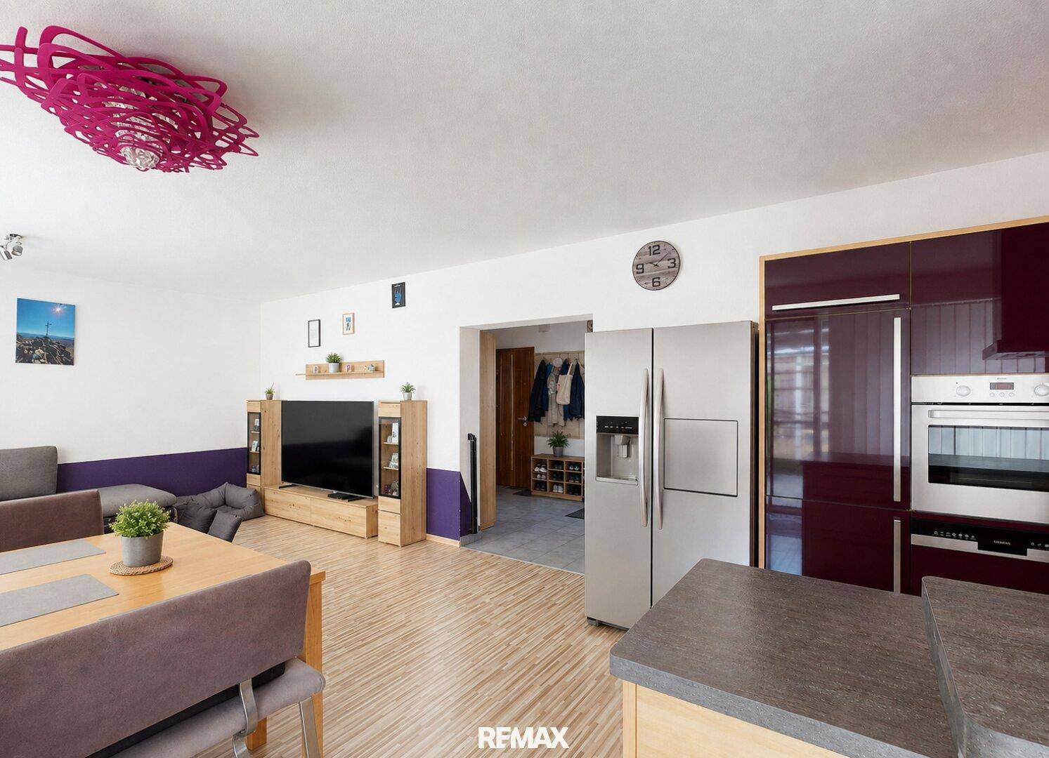 Offener Wohnbereich mit Holzboden, großem Kühlschrank und Zugang zur Küche.
