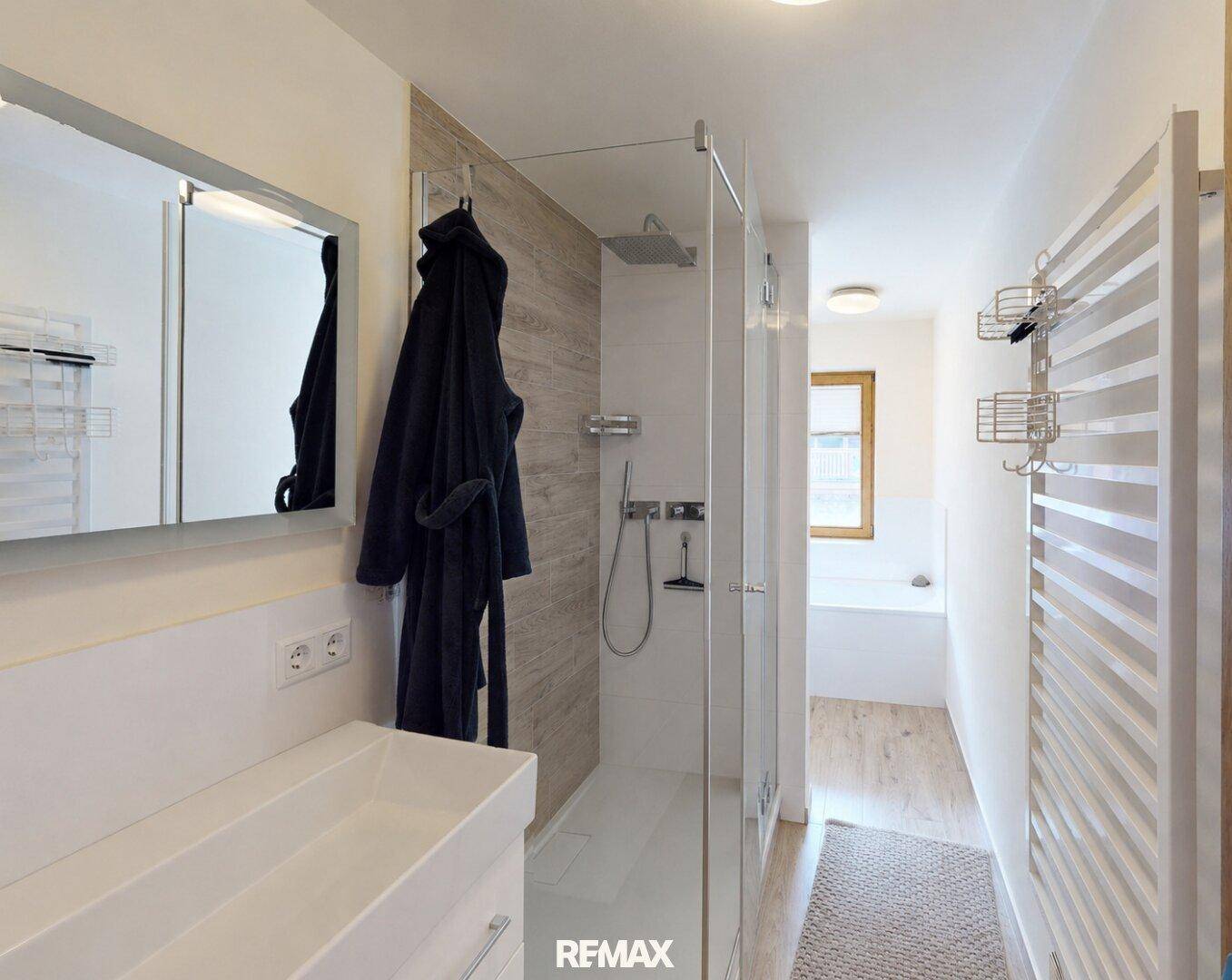 Modernes Badezimmer mit begehbarer Dusche, Waschbecken und beheiztem Handtuchhalter.