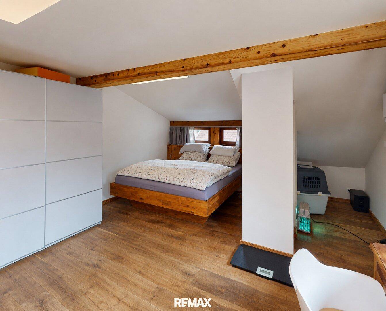Gemütliches Schlafzimmer mit Holzbalken, Einbauschrank und Holzboden.