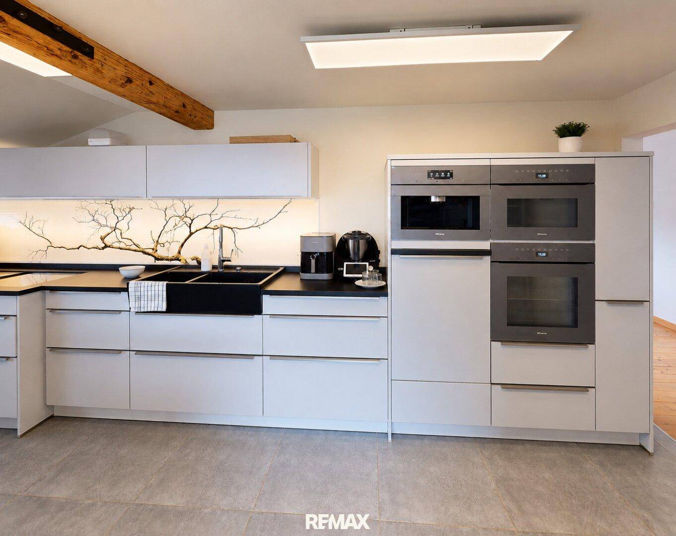 Elegante Einbauküche mit modernen Geräten, weißen Fronten und dunklen Arbeitsplatten.