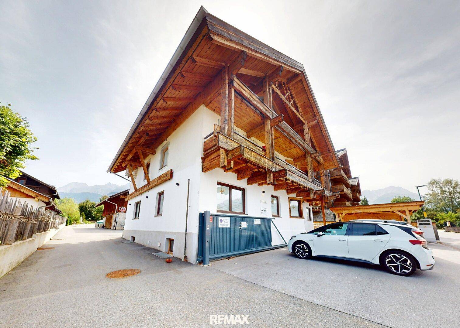 Modernes Gebäude im alpinen Stil mit Holzverkleidung und einem Stellplatz für Fahrzeuge.