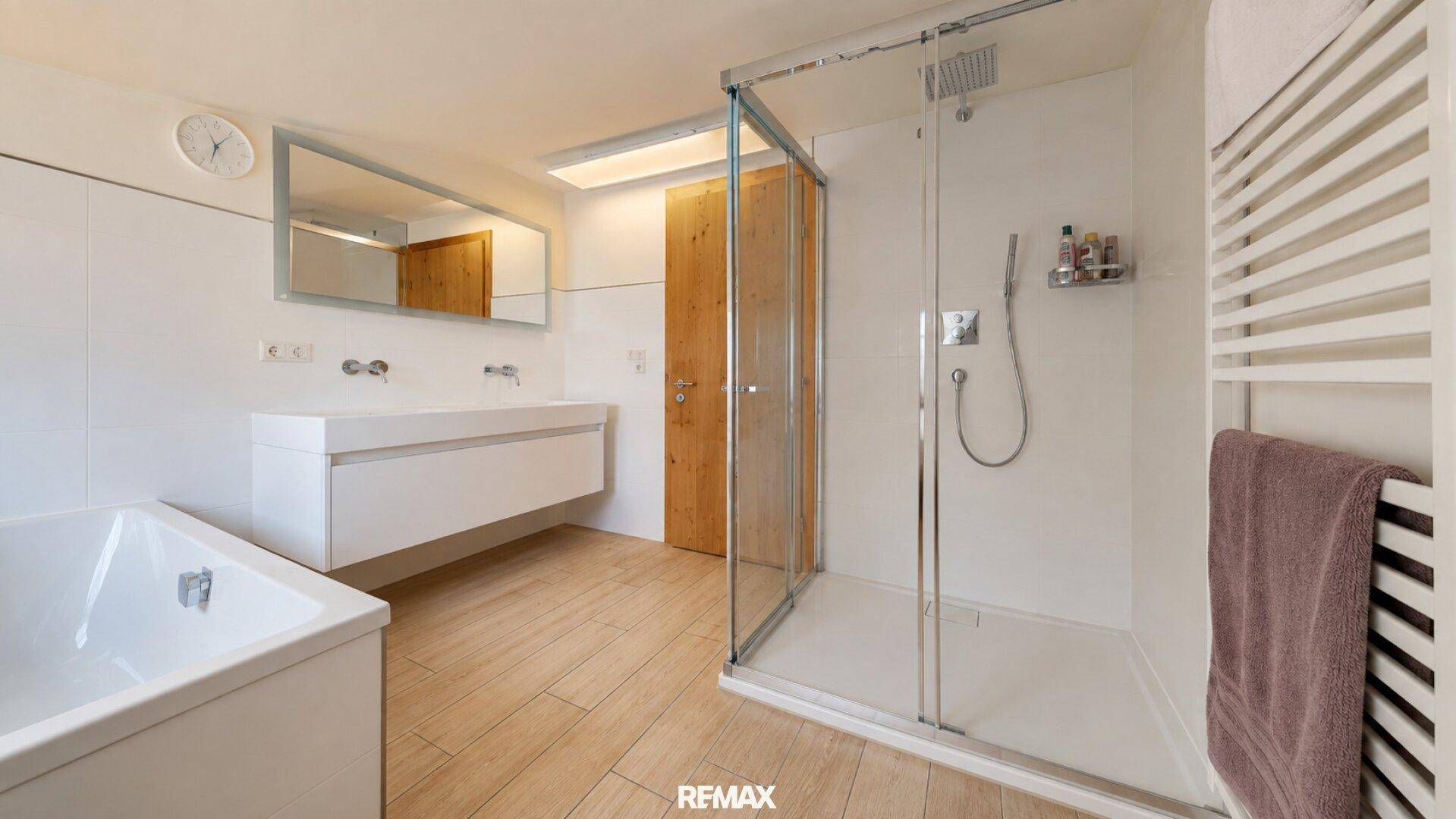 Modernes Badezimmer mit begehbarer Dusche, Badewanne und einem beheizten Handtuchhalter.