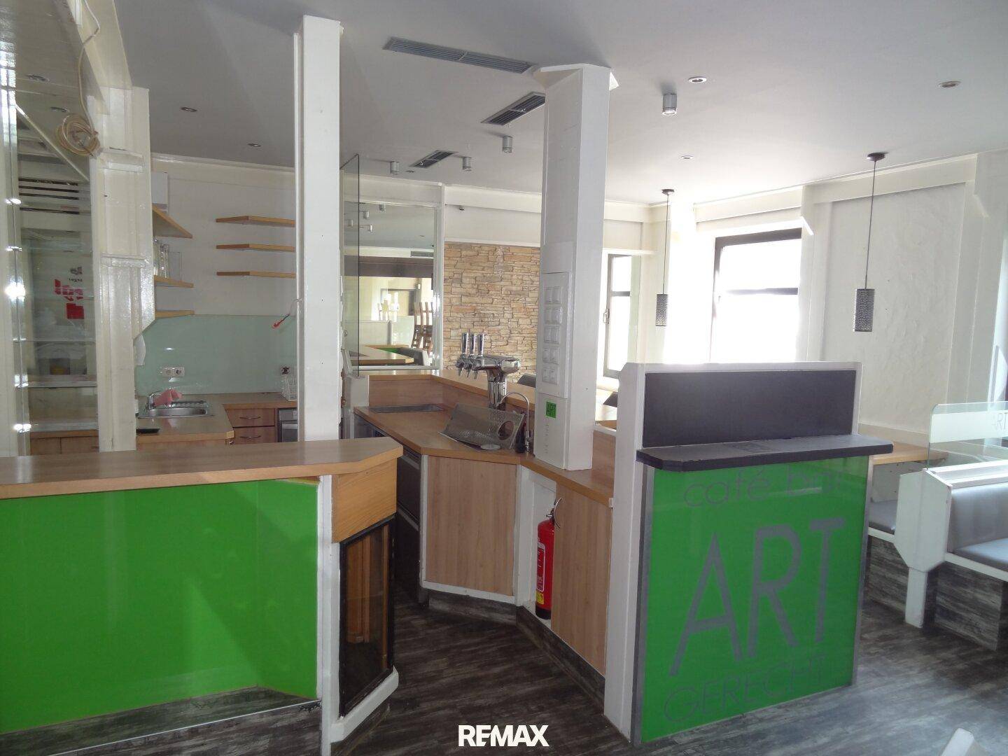 Detailansicht der grünen Bar mit Zapfanlage und Holztheke in einem Gewerberaum, ergänzt durch eine Ziegelwand.
