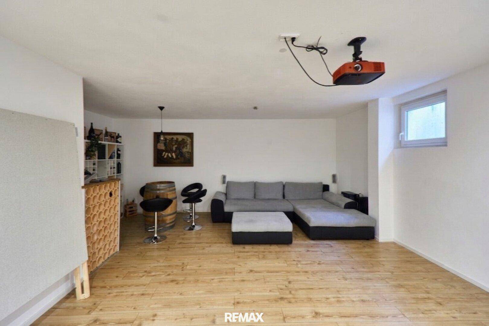 Gemütlicher Medienraum im Untergeschoss mit Beamer, Sofa und Barbereich.