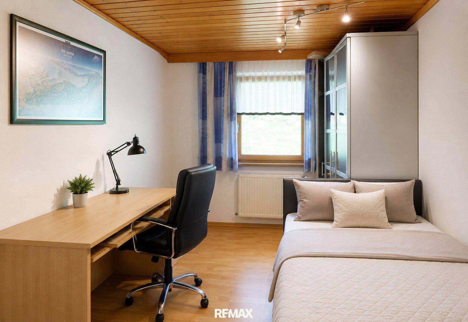 Gemütliches Schlafzimmer mit Einzelbett, Schreibtisch, Kleiderschrank und Holzdecke.