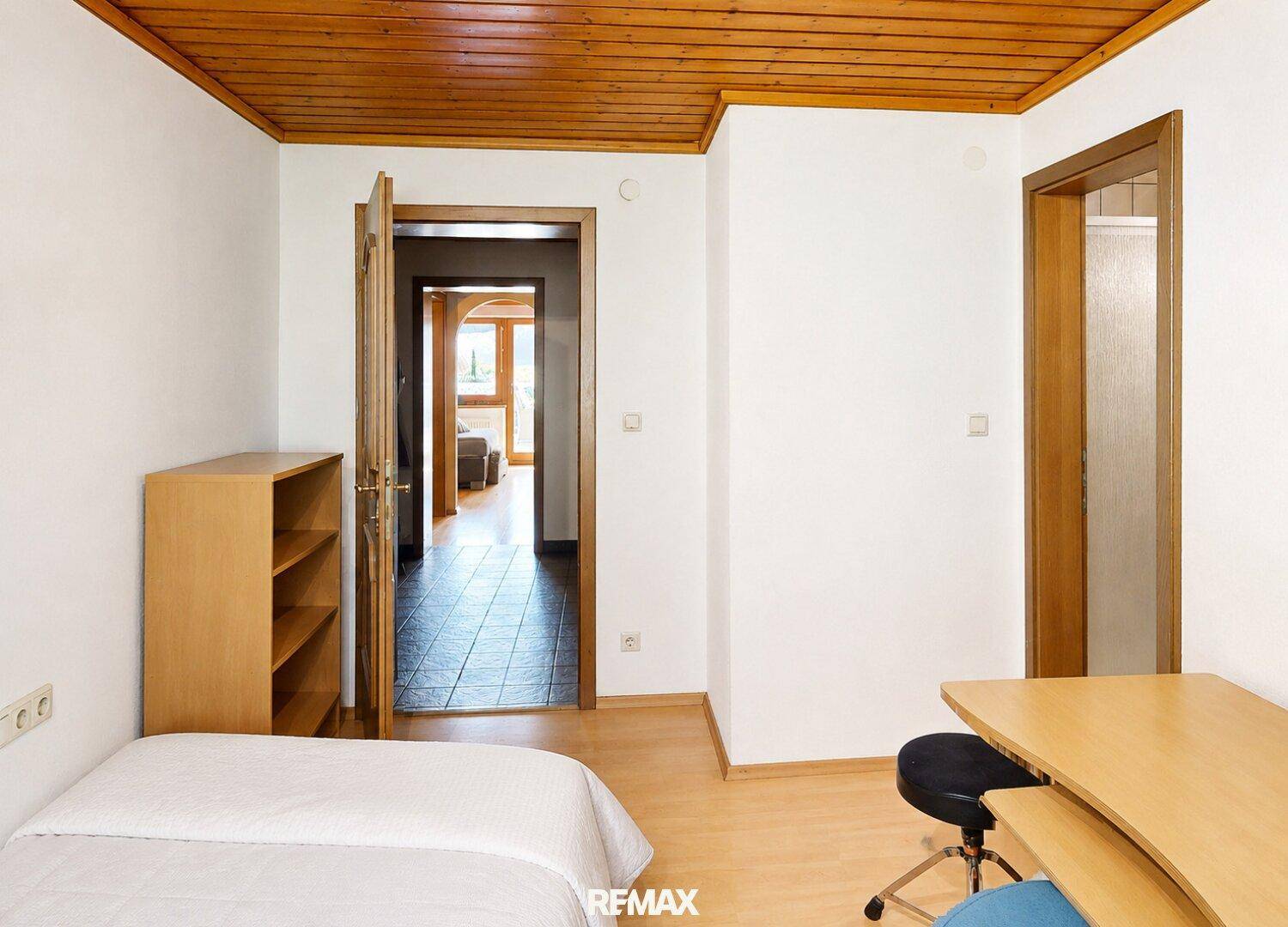 Helles Schlafzimmer mit Holzdecke und Zugang zu einem weiteren Raum mit Fliesenboden.