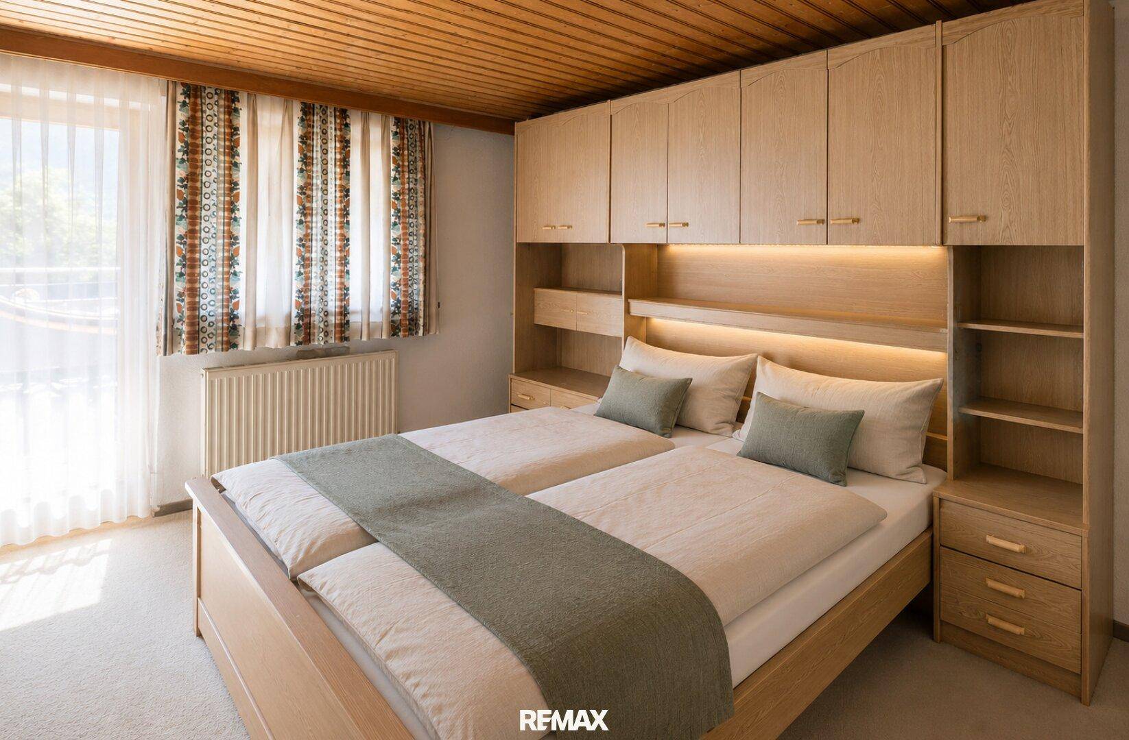 Schlafzimmer mit zwei Einzelbetten, integrierten Holzschränken und einer gemütlichen Holzdecke.