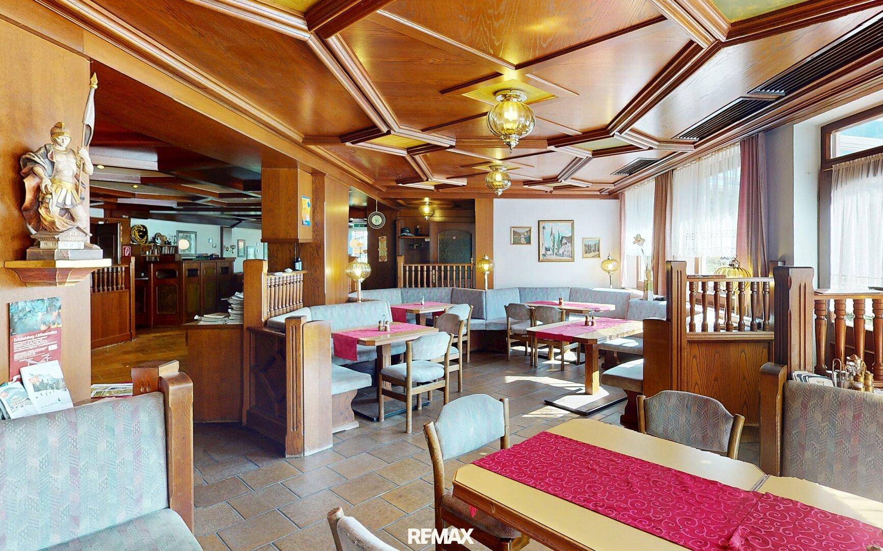 Geräumiger Speisesaal mit aufwendiger Holzvertäfelung, traditionellen Sitzgelegenheiten und Deckenleuchten.