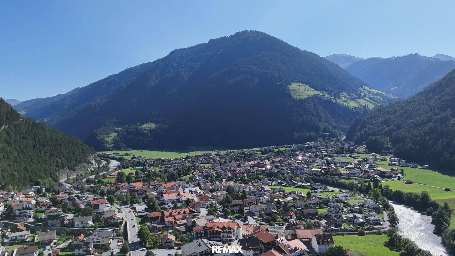 Malerische Luftaufnahme einer Stadt in einem Tal, umgeben von majestätischen Bergen.