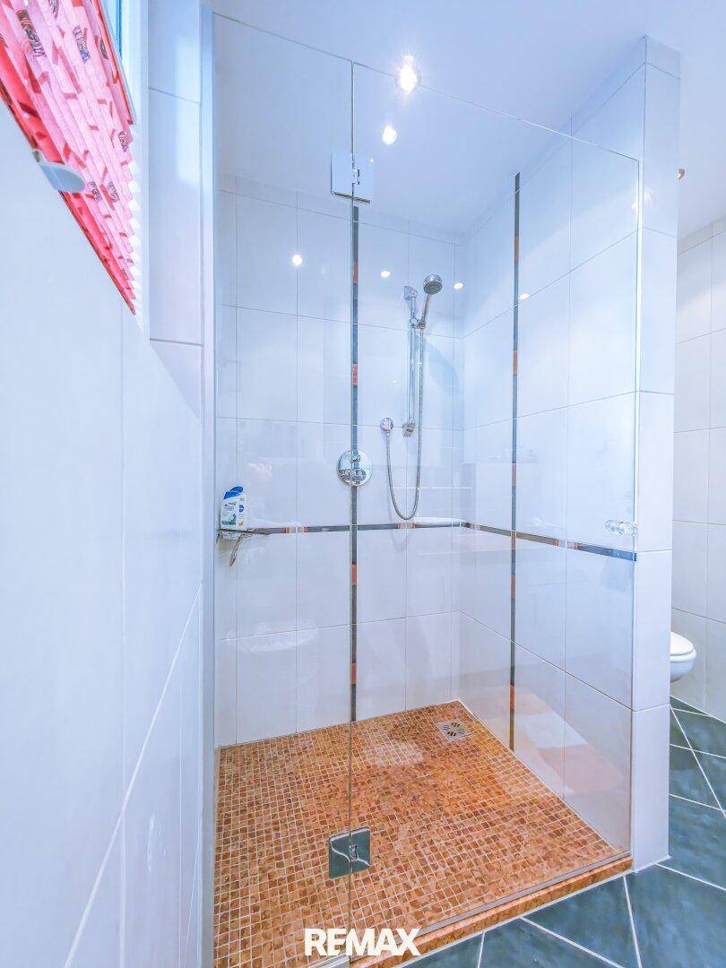 Geräumige Duschkabine mit Glaswänden und Mosaikboden im Badezimmer.