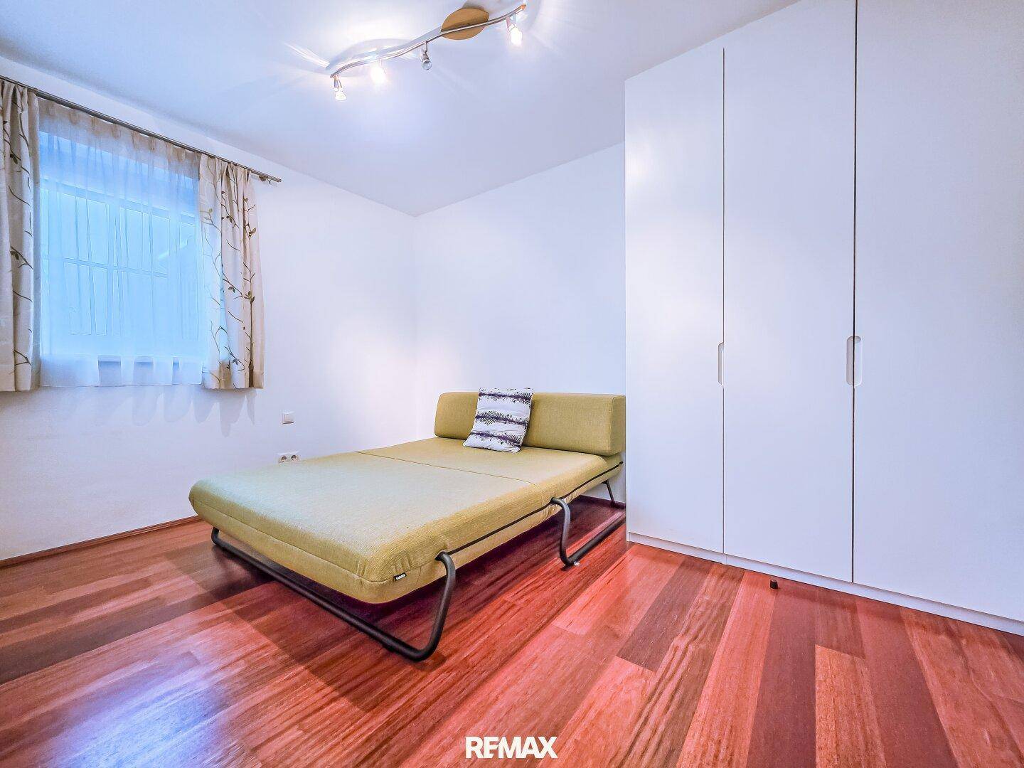 Helles Schlafzimmer mit Einzelbett, Holzboden und Einbauschrank.