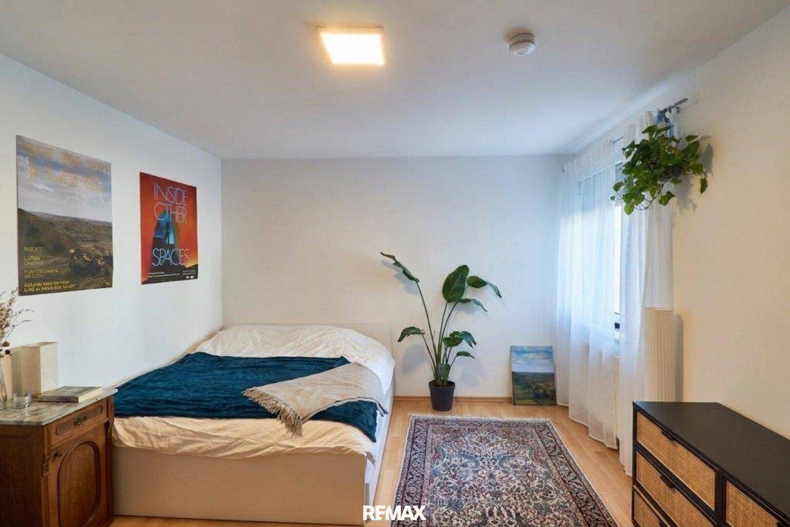 Schlichtes Schlafzimmer mit Holzboden, einem großen Fenster und minimalistischer Dekoration.