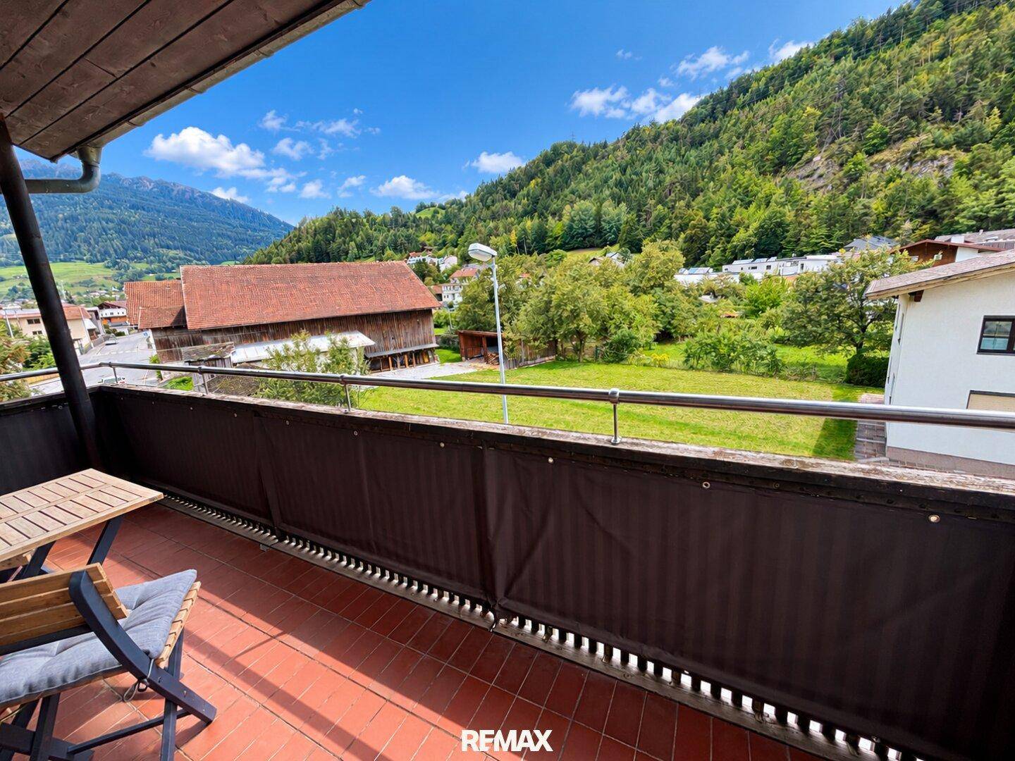 Balkon mit Sitzgelegenheiten und weitem Blick auf grüne Hügel und die umliegende Landschaft.