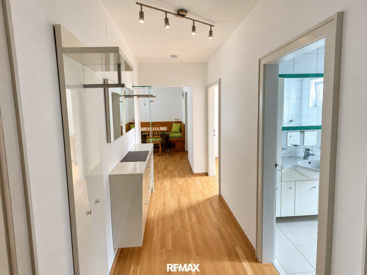 Heller Flur mit Garderobe und Zugang zu verschiedenen Zimmern, inklusive Badezimmer.