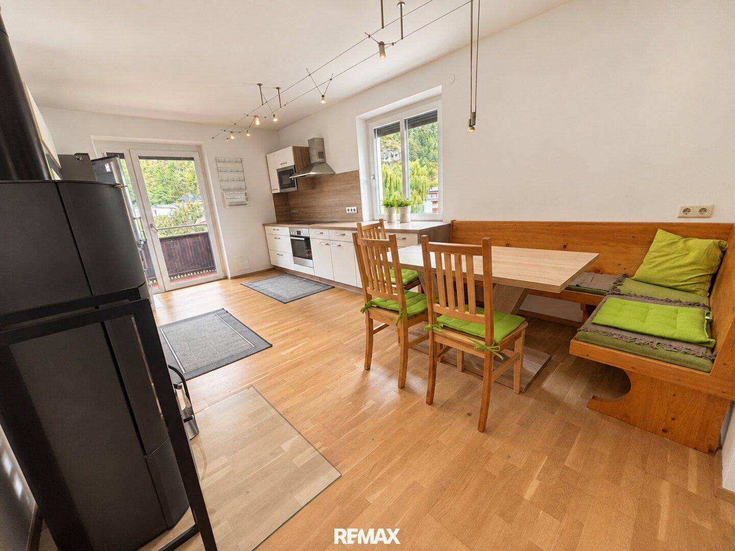 Offene Küche mit Essbereich, Holzofen und direktem Zugang zum sonnigen Balkon.