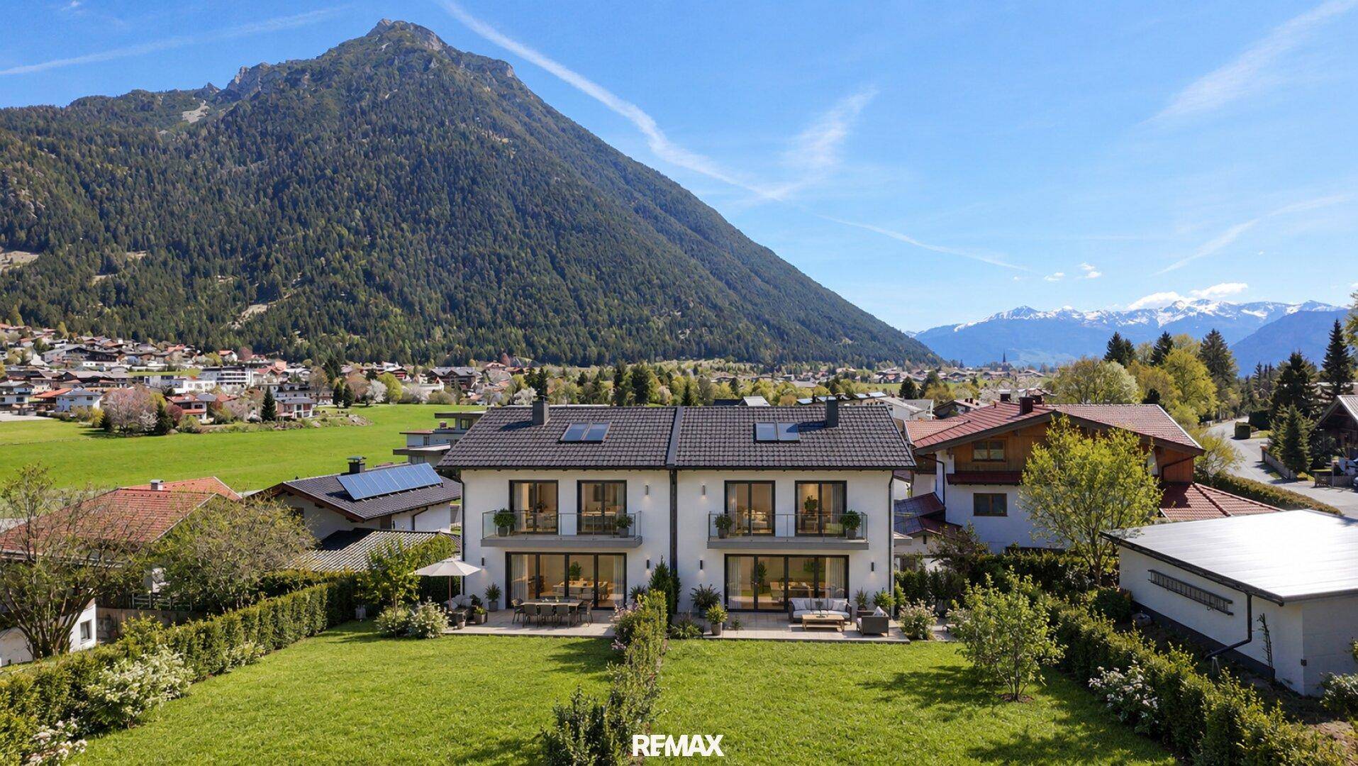 Modernes Doppelhaus mit großzügigem Garten und Panoramablick auf die umliegende Berglandschaft.