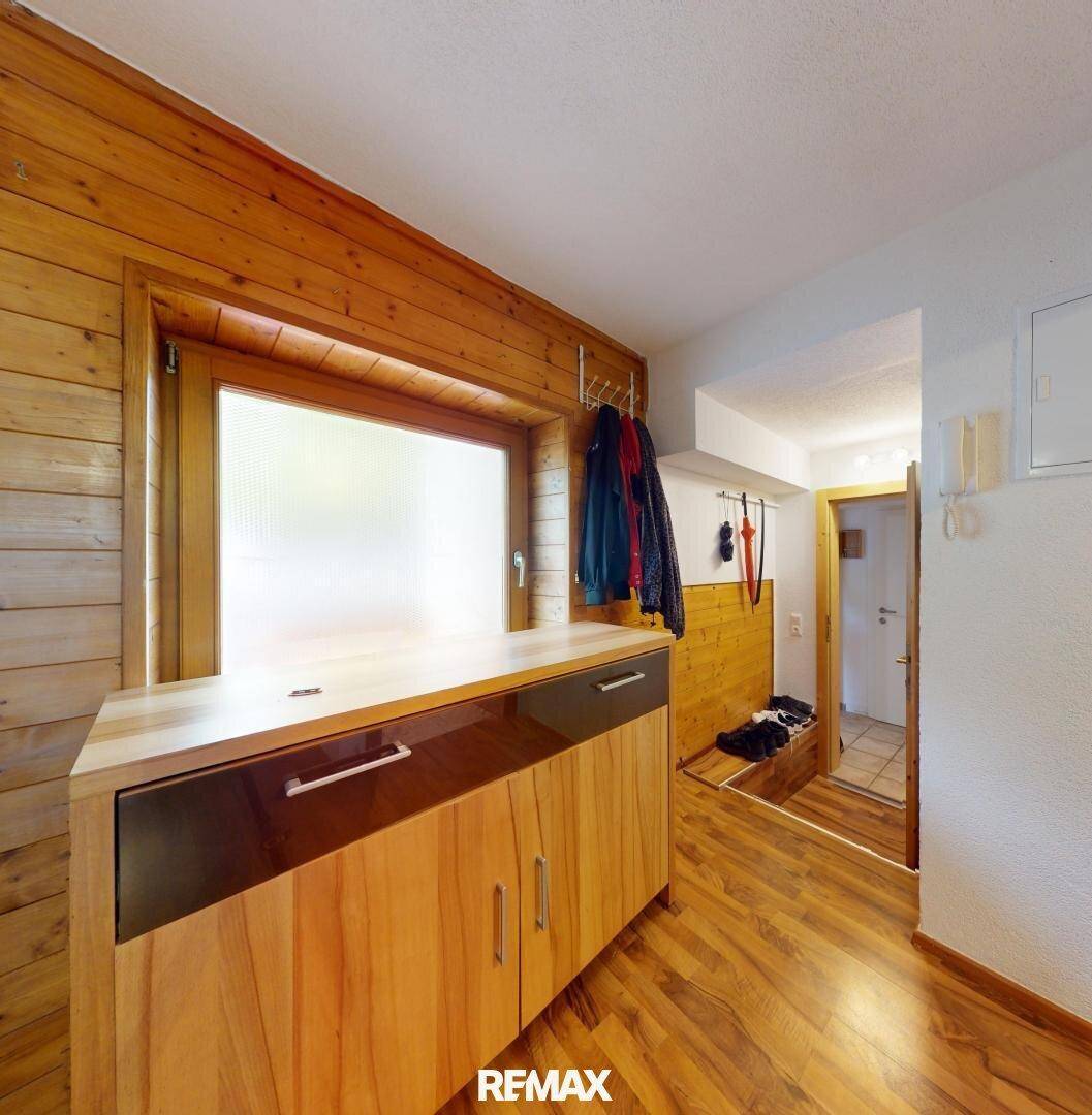 Eingangsbereich mit Holzvertäfelung, Garderobe und einem Fenster für natürliches Licht.