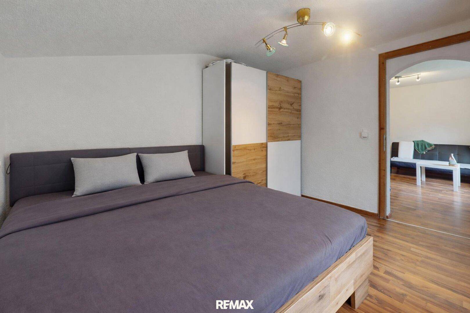 Schlafzimmer mit Doppelbett, Kleiderschrank und direktem Zugang zum Wohnbereich.