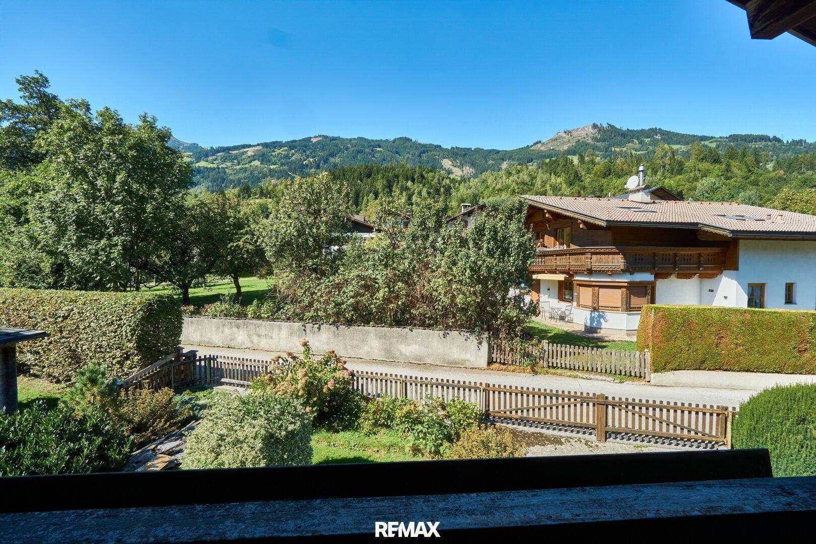 Weitläufiger Ausblick von der Immobilie auf die umliegende grüne Landschaft mit Häusern und Bergen.