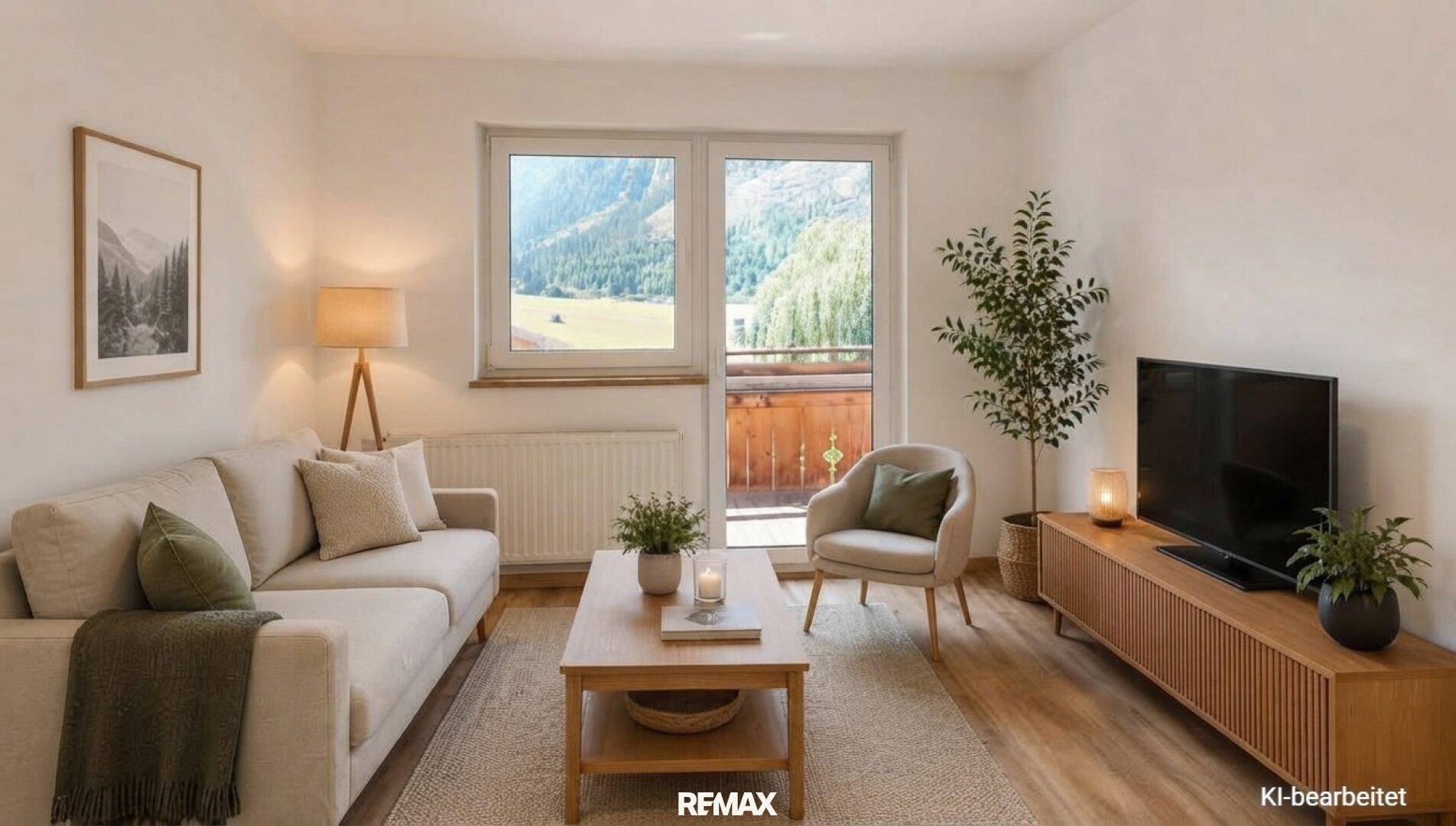 Gemütliches Wohnzimmer mit Sofa, Fernseher und einem weiten Blick auf die Berge.