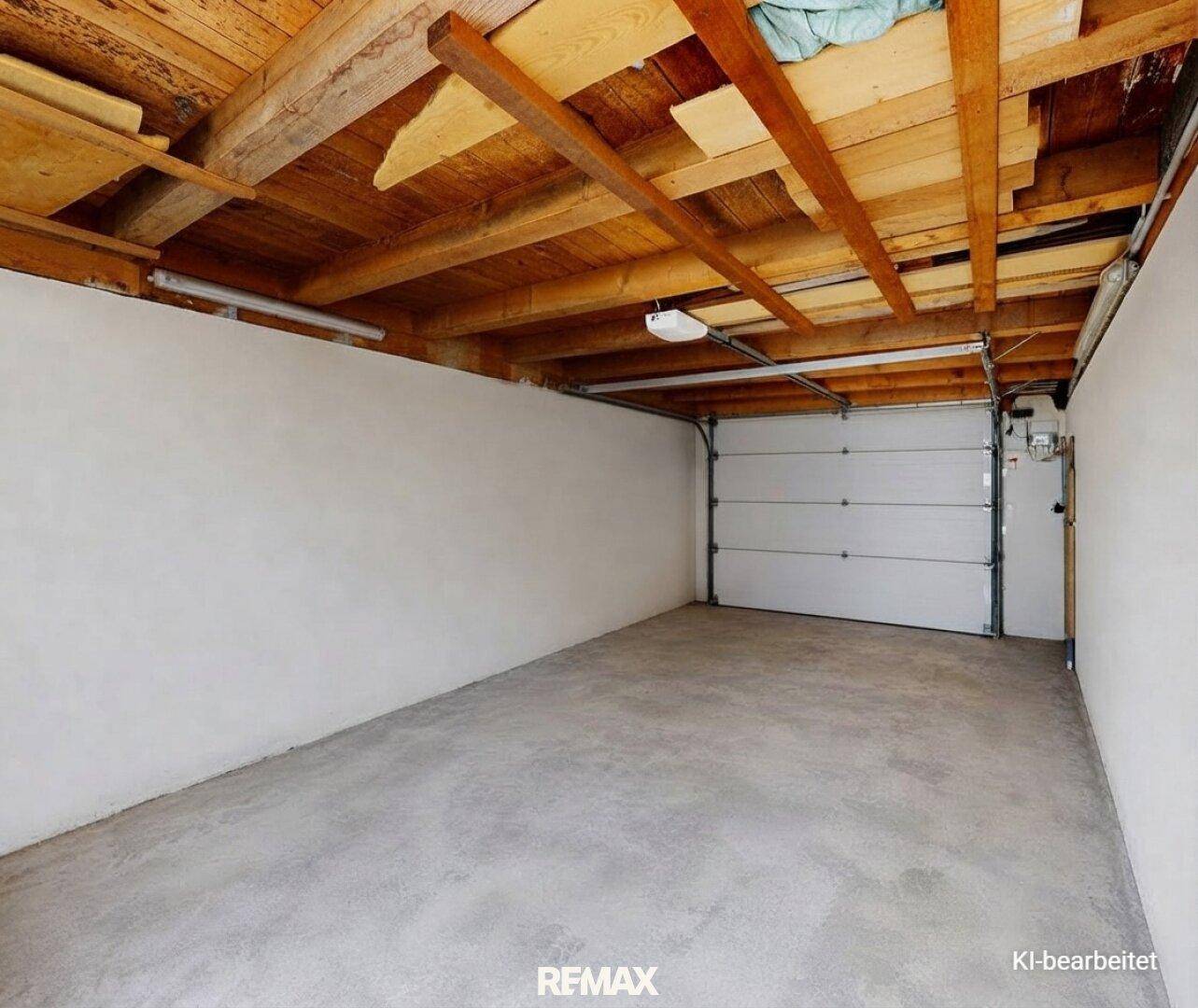 Geräumige Garage mit Betonboden und sichtbarer Holzbalkenkonstruktion an der Decke.