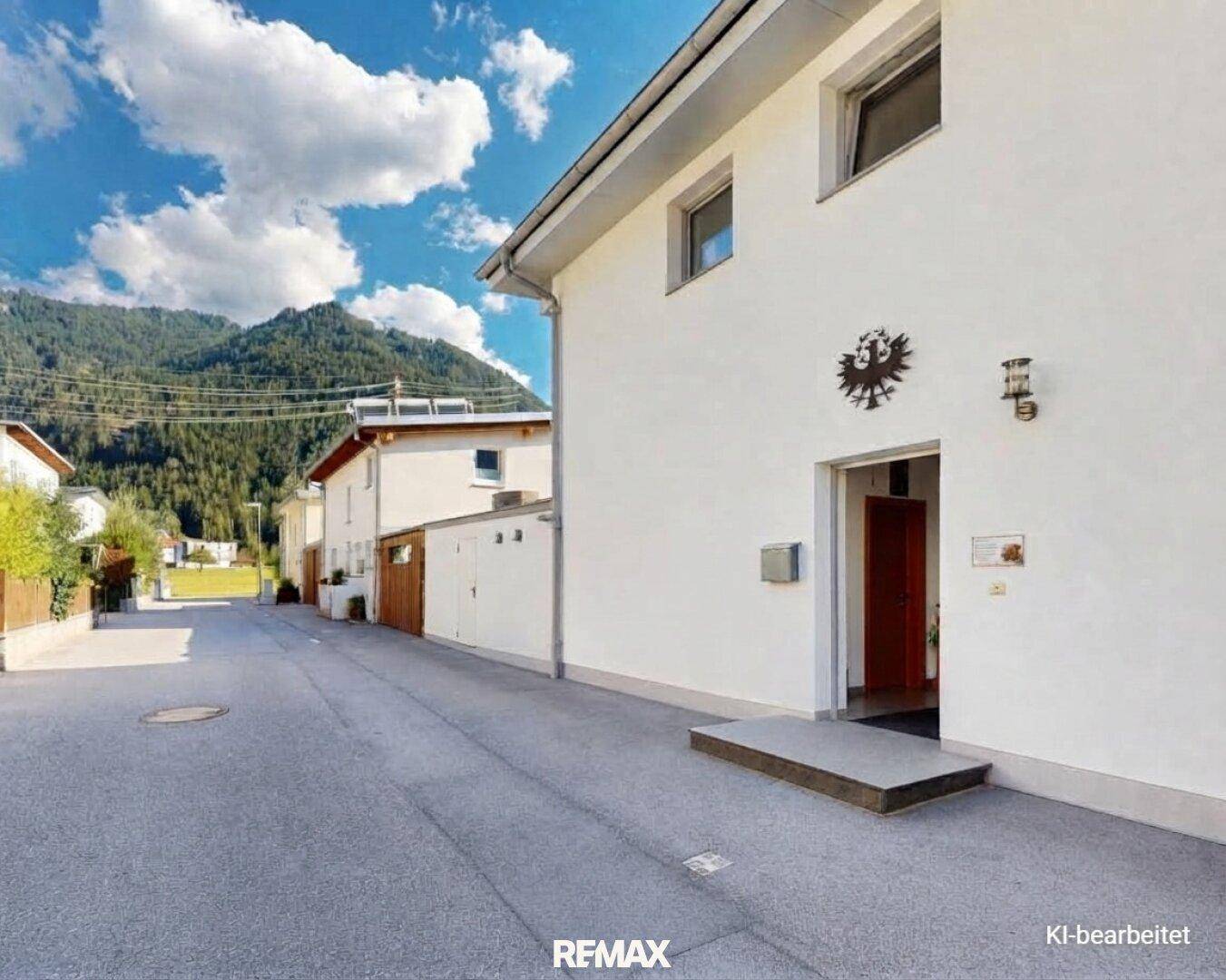 Seitenansicht eines modernen Hauses an einer ruhigen Straße mit Bergblick im Hintergrund.