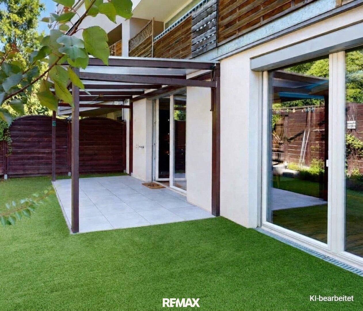Außenansicht des Gebäudes mit überdachter Terrasse und gepflegtem Kunstrasenbereich.