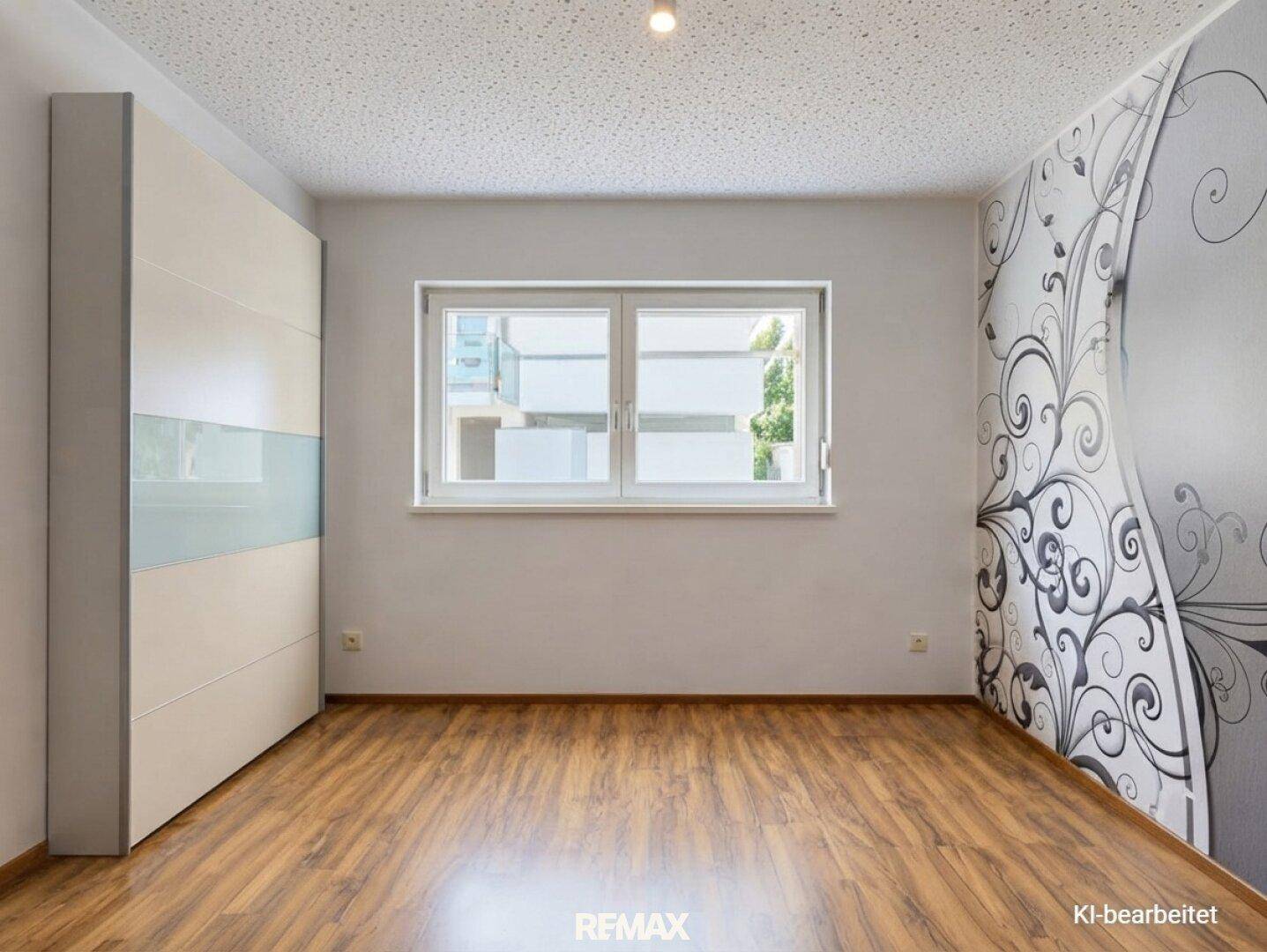 Helles Schlafzimmer mit Holzfußboden, großem Fenster und dekorativer Wandgestaltung.