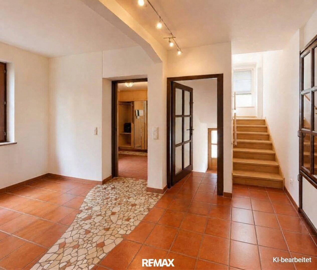 Geräumiger Eingangsbereich mit Terrakottafliesen, dekorativem Mosaikpfad und Holztreppe zu den oberen Etagen.