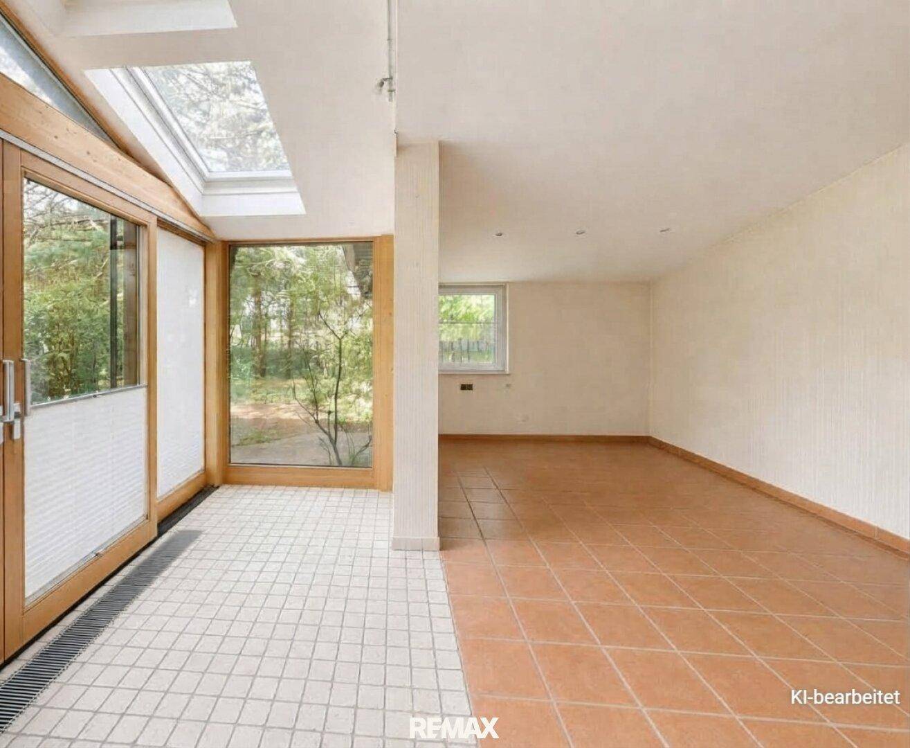 Geräumiger, leerer Wohnbereich mit großen Fenstern, Fliesenboden und Zugang zum Wintergarten.