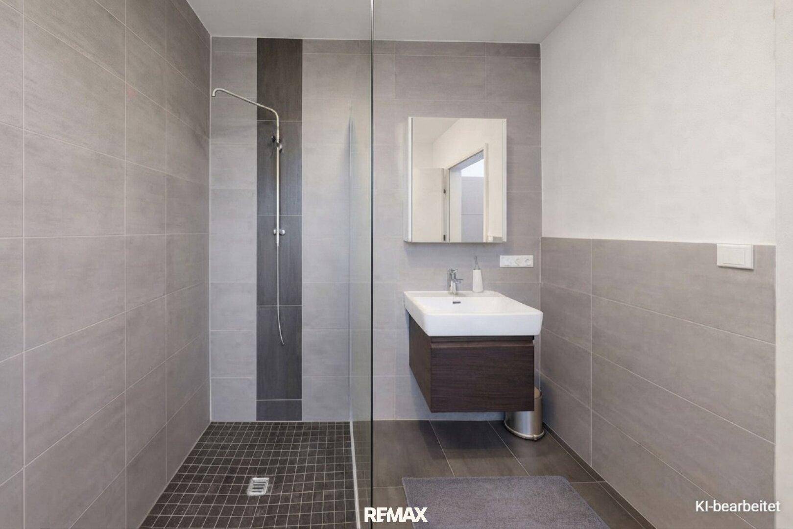 Modernes Badezimmer mit ebenerdiger Dusche, grauen Fliesen und schwebendem Waschtisch.