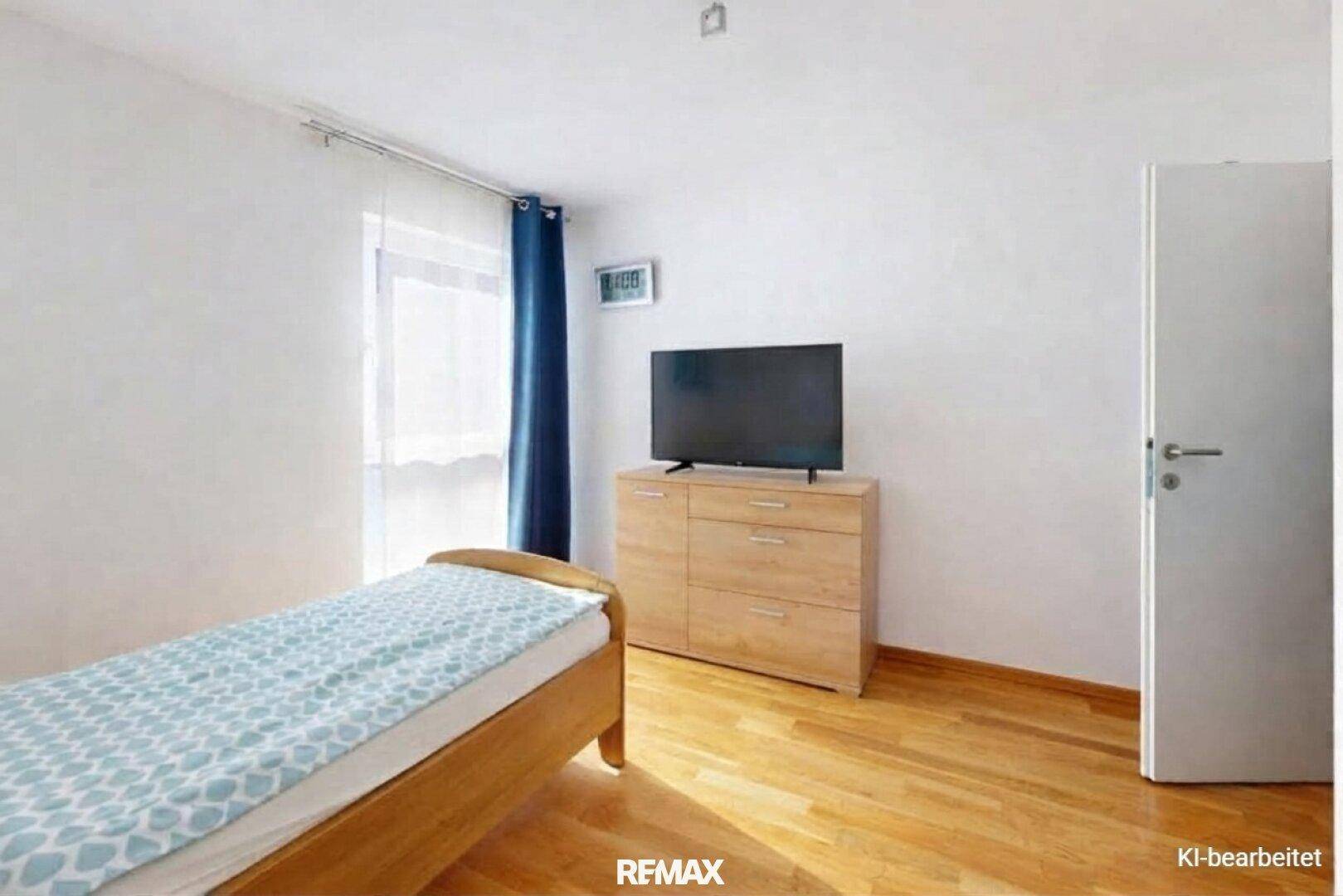 Helles Schlafzimmer mit Einzelbett, Holzkommode und Fernseher, ausgestattet mit Parkettboden.