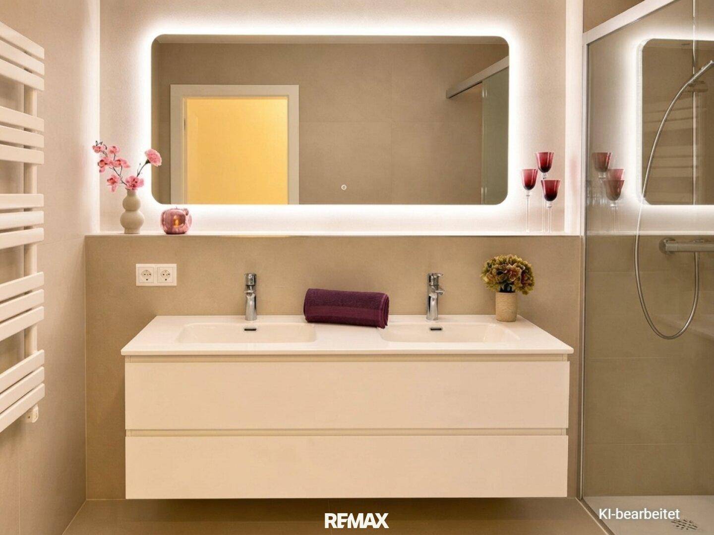 Modernes Badezimmer mit Doppelwaschbecken, beleuchtetem Spiegel und beigefarbenen Fliesen.