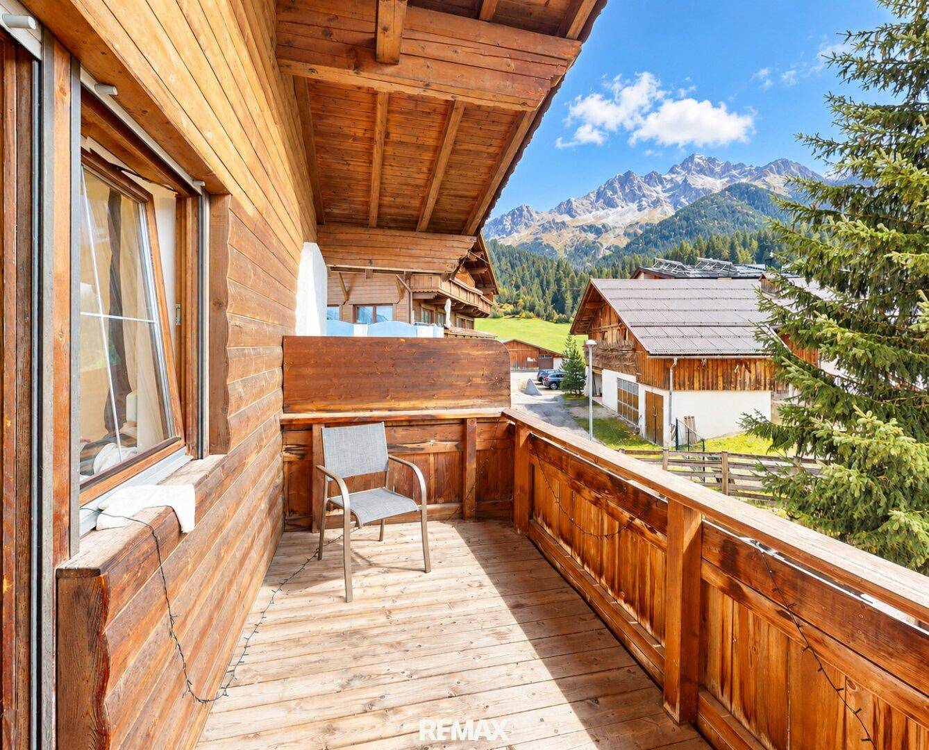 Holzbalkon mit Bergblick und einem Stuhl, um die alpine Landschaft zu genießen.