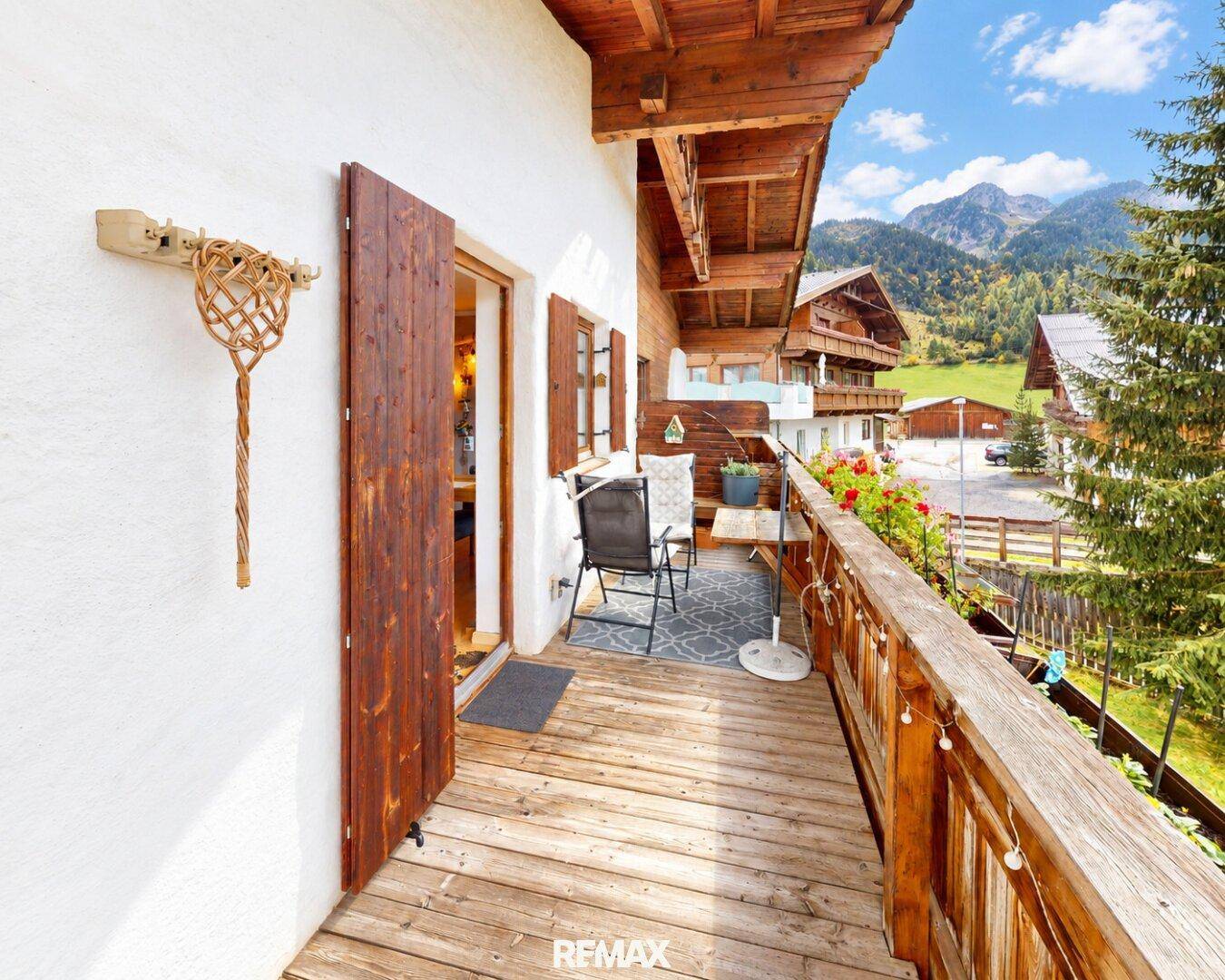 Gemütlicher Balkon mit Sitzgelegenheiten und Blumen, bietet einen schönen Blick auf die Berge.
