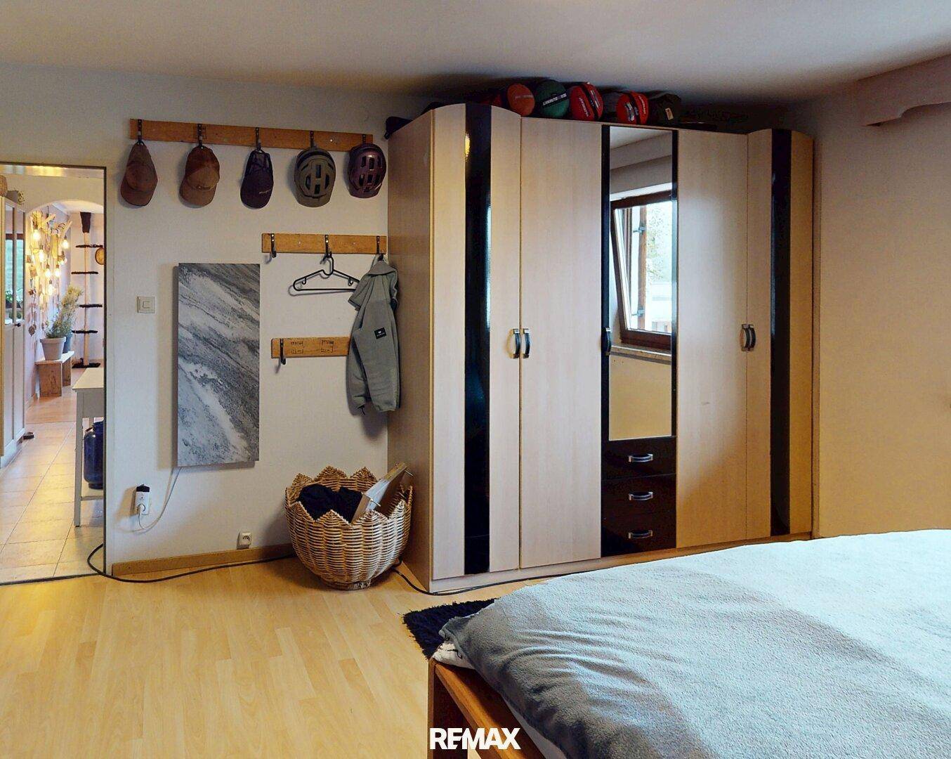 Helles Schlafzimmer mit Holzboden, großem Kleiderschrank und Garderobenbereich.