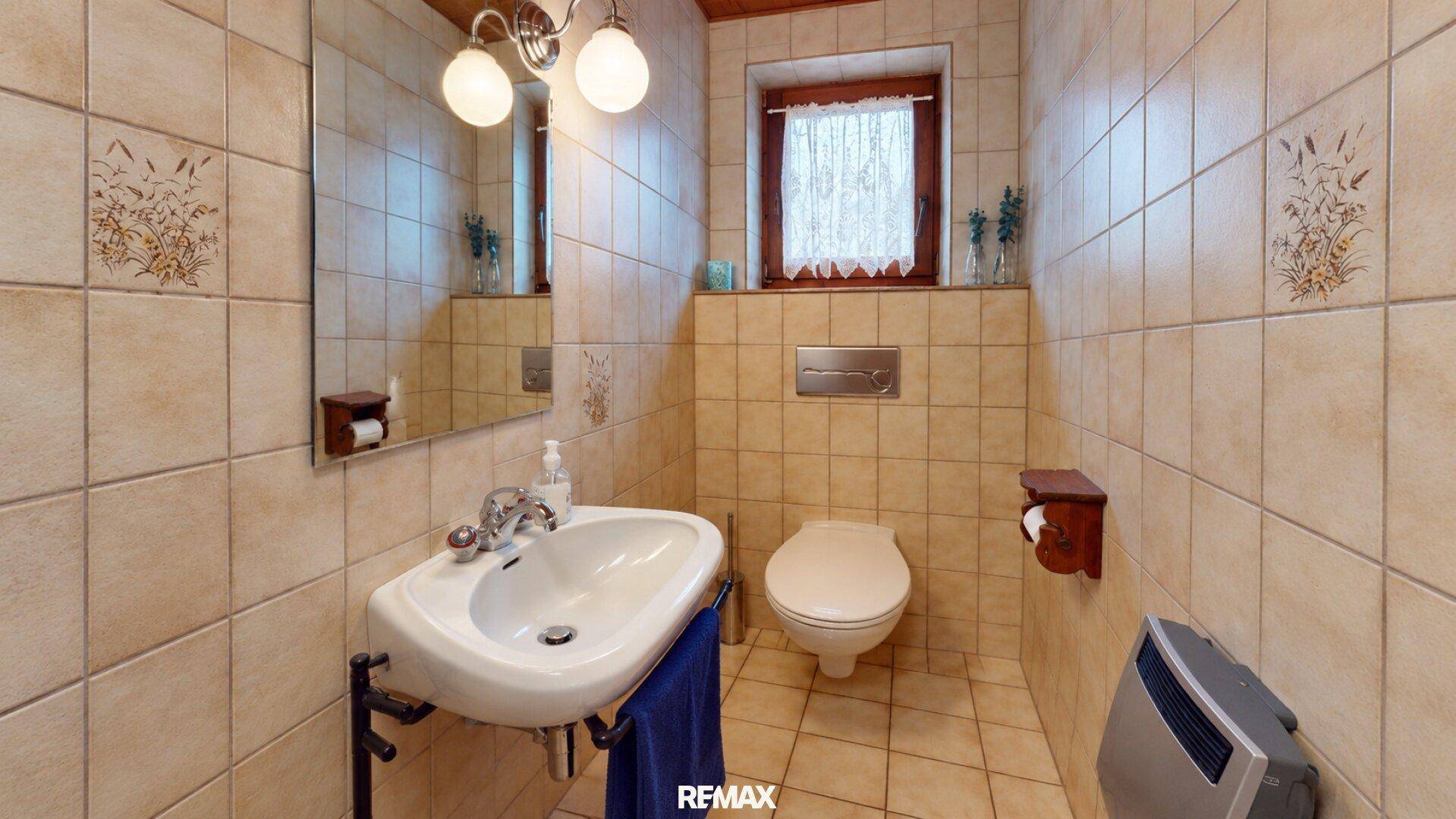 Kleines WC mit Waschbecken, Toilette und beigefarbenen Fliesen im traditionellen Stil.