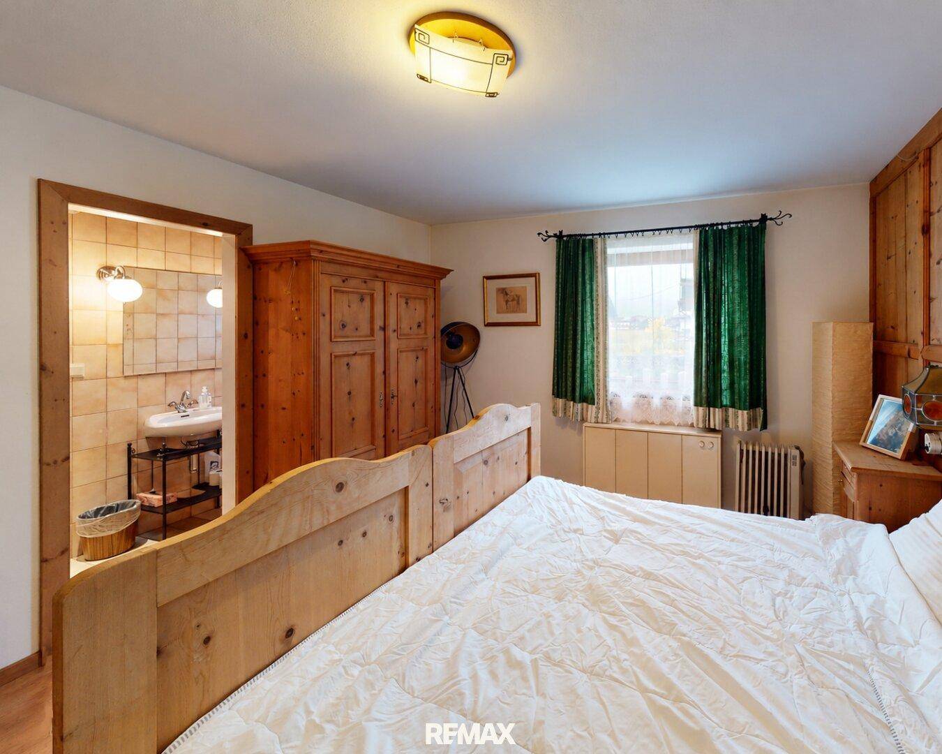 Gemütliches Schlafzimmer mit traditionellen Holzmöbeln und direktem Zugang zum Badezimmer.