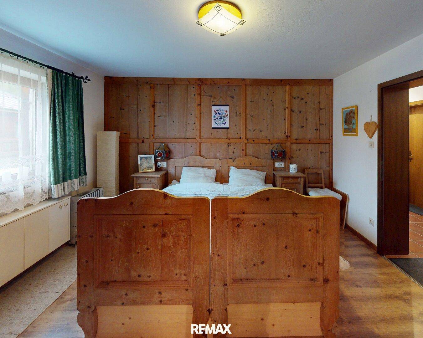 Traditionelles Schlafzimmer mit rustikalem Holzbett und Holzvertäfelung an der Wand.