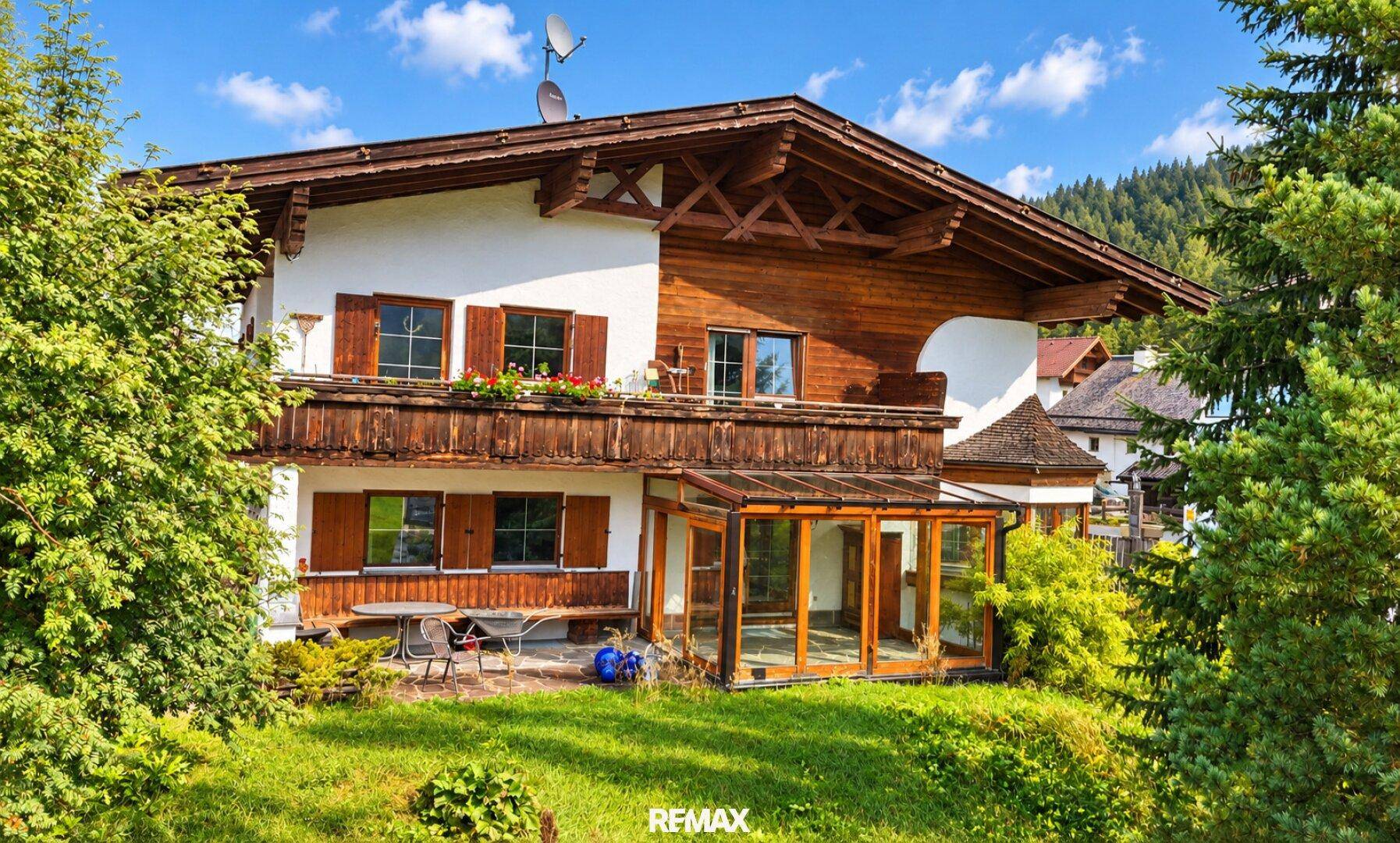 Charmantes Haus im alpinen Stil mit Wintergarten, Balkonen und gepflegtem Gartenbereich.