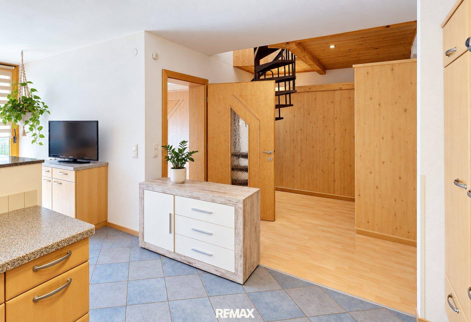 Heller Eingangsbereich mit Fliesenboden, Holzvertäfelung und einer Wendeltreppe.