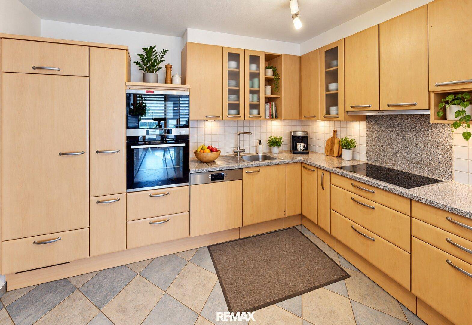 Funktionale Holzküche mit modernen Geräten, Granitarbeitsplatten und Fliesenboden.