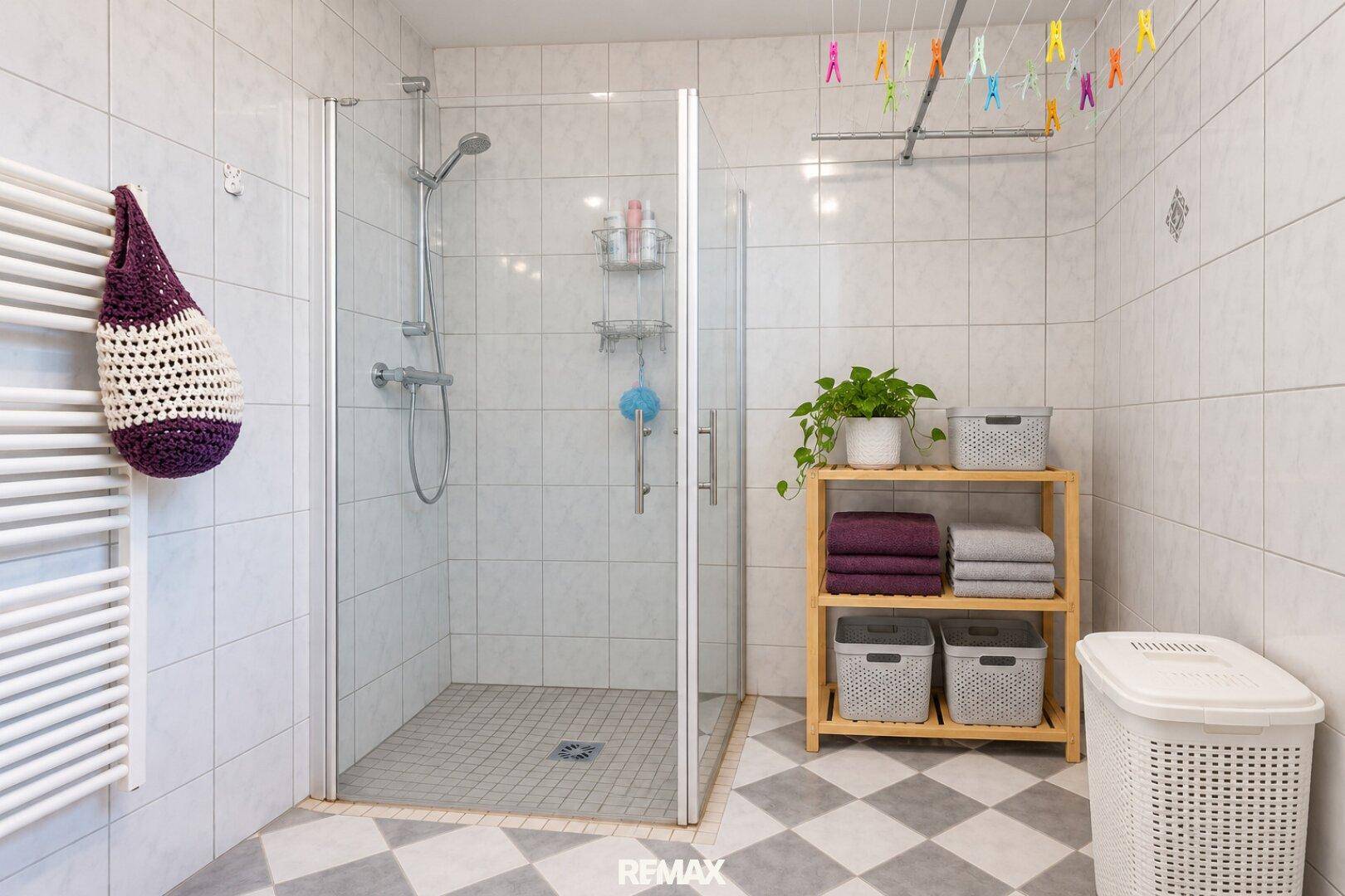 Modernes Badezimmer mit Duschkabine, Handtuchheizkörper und kariertem Fliesenboden.