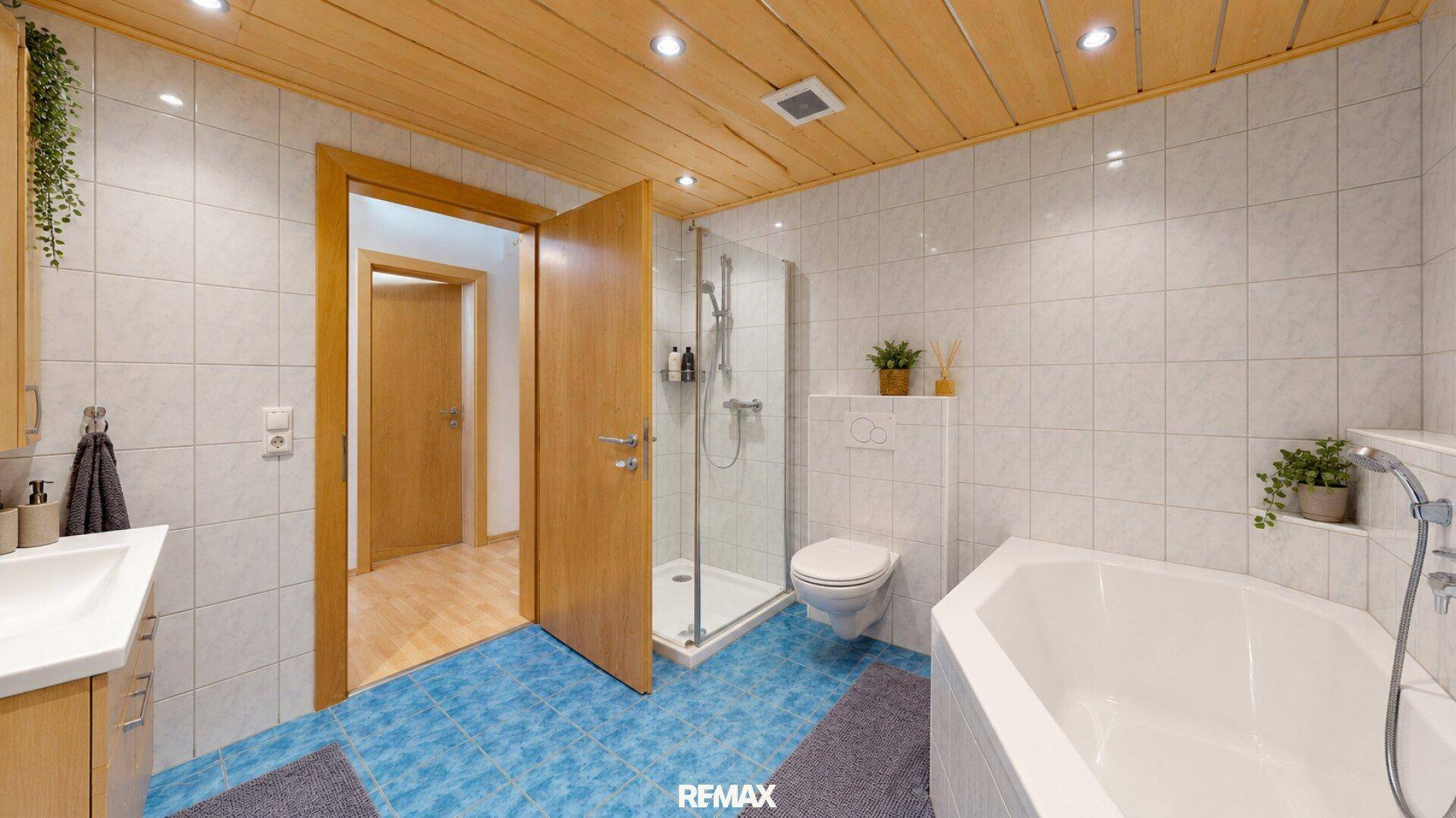 Badezimmer mit Eckbadewanne, Duschkabine und Holzdecke.