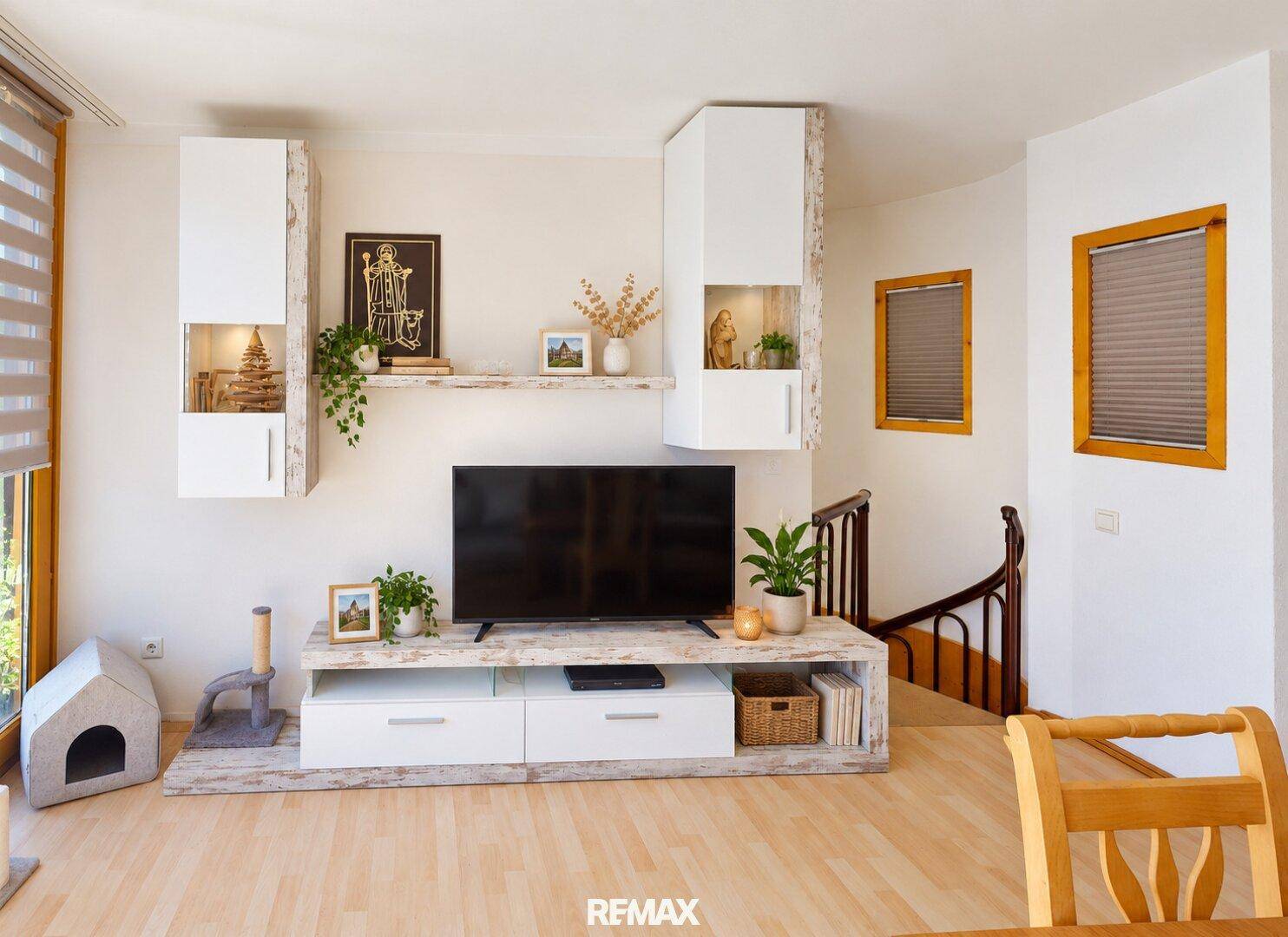 Wohnzimmer mit modernem TV-Möbel, weißen Hängeschränken und Holzfußboden.